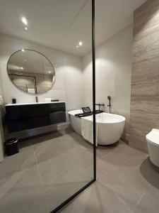a bathroom with a tub and a sink and a mirror at Bij de Haven op Urk in Urk