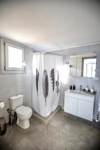 a bathroom with a toilet and a shower curtain with feathers at Seaside Serenade 1, suite in Ermoupoli