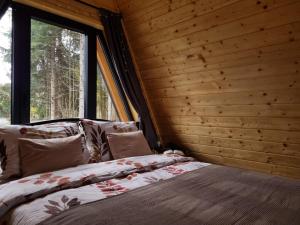a bed in a room with a wooden wall at Gorska bajka - Tisa, planinska kuća za odmor i wellness in Stara Sušica