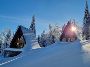 a house covered in snow with the sun shining on it at Gorska bajka - Tisa, planinska kuća za odmor i wellness in Stara Sušica