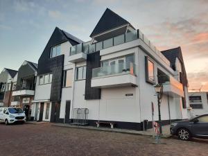 a large white building with a car parked in a parking lot at Bij de Haven op Urk in Urk