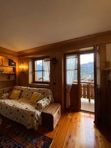 a bedroom with a bed and a couch and windows at Casa con vista a San Vito di Cadore in San Vito di Cadore
