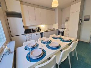 een keuken met een witte tafel met borden en stoelen bij Spacious apartment with balcony and free WiFi in Rovaniemi