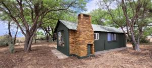 una pequeña casa con chimenea de ladrillo en la parte superior en Soetdorings Farmstay Karoo Chalet, en Beaufort West