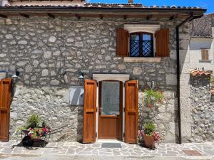 een stenen huis met een houten deur en ramen bij Baita delle Rocche in Rocca di Mezzo