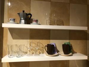 a shelf with glasses and cups and a tea kettle at TIF Studio in Râmnicu Vâlcea