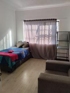 um quarto com uma cama, uma janela e um sofá em Inspire living home em Benoni