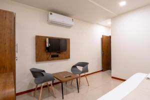 Zimmer mit 2 Stühlen, einem Tisch und einem TV in der Unterkunft hotel silver tree in Rajkot