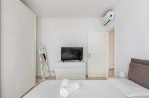 a white living room with a couch and a television at Formigine - [Motor Valley-Homes] in Formigine