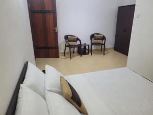 a bedroom with a bed with two chairs and a mirror at M-stay Colombo in Sri Jayewardenepura Kotte