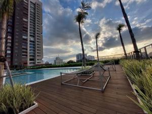 a pool with palm trees and chairs on a wooden deck at Book Sampa Studio 263A Lume - Alto da Boa Vista in Sao Paulo