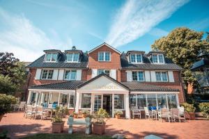 um edifício com cadeiras e mesas em frente em Strandhotel Strande em Strande