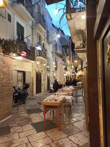 una strada con tavoli e sedie in un vicolo di Corte Barone a Bari