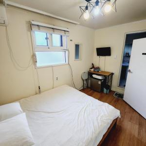 a bedroom with a white bed and a window at Joy Guesthouse in Seoul