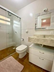 a bathroom with a toilet and a glass shower at Ap 2 dormitorios no centro in Capão da Canoa