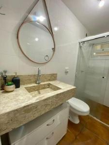 a bathroom with a sink and a toilet and a mirror at Ap 2 dormitorios no centro in Capão da Canoa