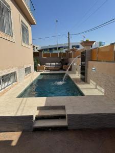 a swimming pool with a fountain in front of a house at Spacieuse villa familiale avec piscine Founty in Agadir