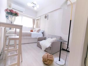 a small white room with a bed and a couch at Z87新宿最中心 東新宿站5分-Shinjuku center 5 mins to Station, Max 3P 新宿 涉谷 表参道 池袋 上野 代代木 银座 原宿 in Tokyo