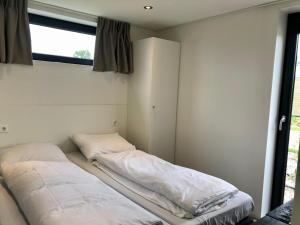 twee bedden in een kamer met een raam bij Enkhuizer Strand Cube Elite Hafenpanorama mit Dachterrasse Haus Nr 339 in Enkhuizen