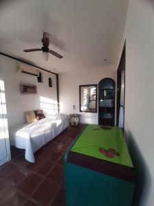 1 dormitorio con cama y mesa verde en Pousada Chez Moi en Cabo Frío