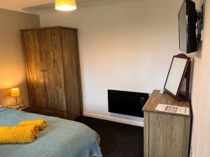 a hotel room with a bed and a flat screen tv at Green Cottage in grounds of Grade II* Frognal Farmhouse in Sittingbourne