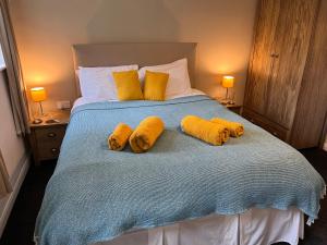 Una cama con almohadas amarillas encima. en Green Cottage in grounds of Grade II* Frognal Farmhouse, en Sittingbourne