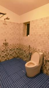 a bathroom with a toilet in a tiled room at Mitra Hostel Vagator in Vagator