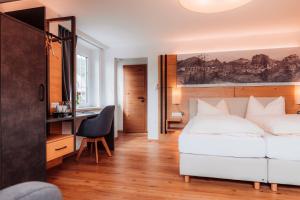 a bedroom with a white bed and a desk at Hotel Payerbacherhof in Payerbach