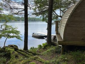 a boat sitting on the water next to a cabin at Moose Cabin - Cozy Forest Retreat nearby Lake in East Kemptville