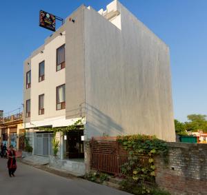 een vrouw loopt langs een hoog gebouw bij Hotel NEU-NEST in Rishīkesh