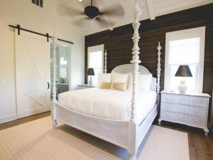 a bedroom with a white bed and a wooden wall at Kaya Cottages in Dahlonega