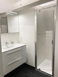 La salle de bains blanche est pourvue d'une douche et d'un lavabo. dans l'établissement L'appartementducroisic - Sur le port, vue mer, au Croisic