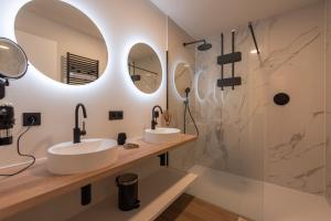 two sinks in a bathroom with mirrors and a shower at NIEUW De Grenspaal NOORD 6P - 3SLPK 5 min Maastricht - SAUNA - LAADPAAL in Riemst
