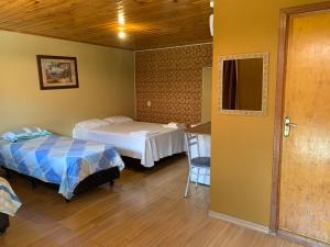 a room with two beds and a table and a mirror at Pousada avenida in Urubici