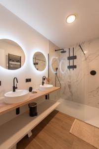 a bathroom with two sinks and two mirrors at NIEUW De Grenspaal NOORD 6P - 3SLPK 5 min Maastricht - SAUNA - LAADPAAL in Riemst