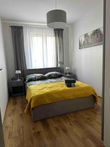 een slaapkamer met een bed met een gele deken en een raam bij ApartBroniewskiego in Toruń