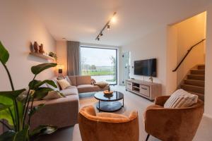 sala de estar con 2 sofás y TV en NIEUW De Grenspaal NOORD 6P - 3SLPK 5 min Maastricht - SAUNA - LAADPAAL, en Riemst