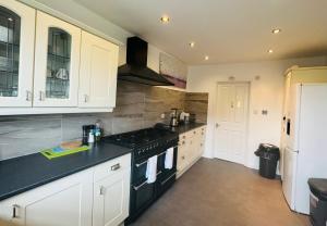 a kitchen with white cabinets and a black stove top oven at Chic 5 Bedroom House with Private Parking & Garden in Bristol