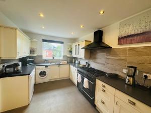 a kitchen with white cabinets and a stove top oven at Chic 5 Bedroom House with Private Parking & Garden in Bristol