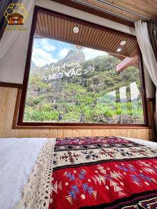 łóżko w pokoju z dużym oknem w obiekcie Mèo Vạc Beehive House w mieście Mèo Vạc