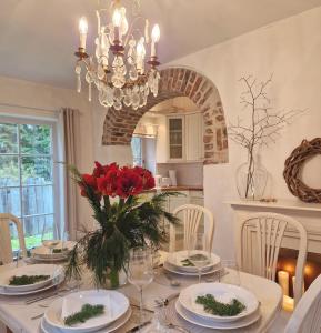 a dining room with a table with red flowers on it at Ferienhaus Rosenhof in Weidenbach