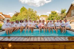 un grupo de personas con camisas blancas sentadas en una piscina en Maison d'hôte privatisée avec piscine et jacuzzis 15 pers max en La Couture-Boussey