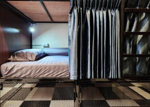 a bed in a room with a curtain at Noir Cafe And Hostel Chinatown Bangkok in Pom Prap