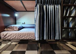 a bed in a room with a curtain at Noir Cafe And Hostel - Chinatown Bangkok in Pom Prap