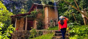 a woman walking in front of an old house at Eco-Hotel Mayachik in San Juan La Laguna