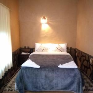 a bedroom with a bed and a light on the wall at La perle de saghro in Nkob