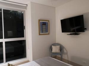 um quarto com uma cama, uma televisão e uma cadeira em Edificio Murano Elite Apartamento 3 habitaciones- Hermosa vista al mar em Cartagena das Índias