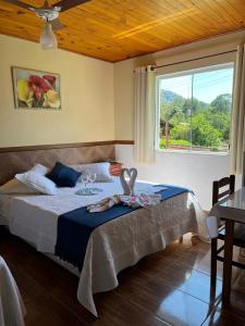 sypialnia z dużym łóżkiem i oknem w obiekcie Pousada Sabor da Serra w mieście Visconde De Maua