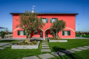 un edificio rojo con dos árboles delante de él en Borgo degli Ulivi, en Formigine