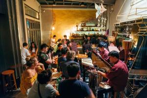 Noir Cafe And Hostel Chinatown Bangkok في Pom Prap: مجموعة من الناس يجلسون في حانة